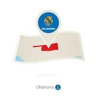 Folded paper map of Oklahoma U.S. State with flag pin of Oklahoma. vector