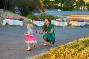linda madre con un encantador bebé hija camina en el ciudad parque foto