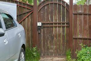 Wooden gate with a brown fence and a car in the village photo