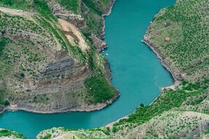 mountain landscape, a deep canyon with a blue river at the bottom, a camp site and a road under construction photo