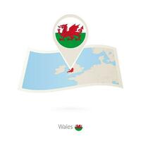 Folded paper map of Wales with flag pin of Wales. vector