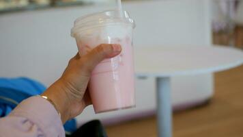 Strawberry drink or Pink drink cup held by hand from the side photo