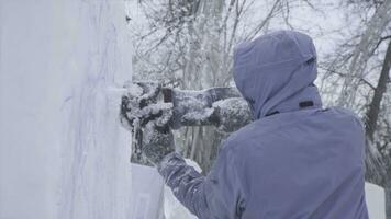 View of sculptor carving ice. Movement. Cut ice with a chainsaw. Cut and make snow sculpture. Chopping iced water with an axe. Ice Sculpture Carving. V-LOG photo