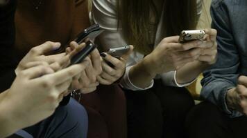 Closeup of friends chatting on mobile phone in network. Group of friends are using gadgets during recreation time at home. Friends sitting and chatting in the phone closeup photo