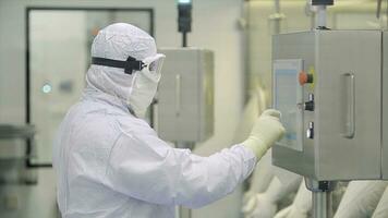 Worker At Pharmaceutical Factory. Lab technician working inside a pharmaceutical factory. Pharmaceutical manufacturing. Operating control panel of the pharmaceutical machine photo