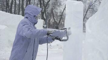 View of sculptor carving ice. Movement. Cut ice with a chainsaw. Cut and make snow sculpture. Chopping iced water with an axe. Ice Sculpture Carving. V-LOG photo