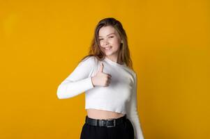 Young caucasian woman showing thumbs up against bright yellow background photo