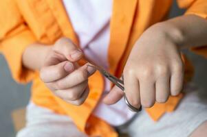 Manicure scissors in the hands of a child cut nails. Boy cutting his nails photo