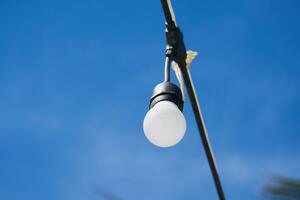 Light bulb on a wire with blue sky on the background. photo