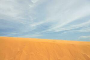Sand dune in the desert with clouds in the background photo