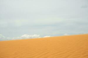 Sand dune in the desert with clouds in the background. photo