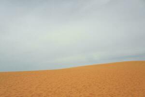 Sand dune in the desert with clouds in the background. photo