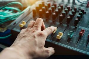 Close-up hand adjusting mixer sound on audio panel photo