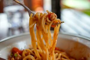 Close-up fork scooping spaghetti pork sauce photo