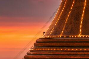 Buddhists climb up to light decoration the golden pagoda Phra Pathom Chedi on sunset sky in annual festive at Nakhon Pathom photo