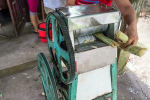 Crush machine working with crushed sugar cane in store photo