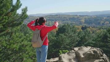 een vrouw met een rugzak Aan haar terug Aan de top van een berg looks Bij de landschap. meisje reiziger geniet vakantie, reis, avontuur. Kaukasus bergen, visie van elbroes. video