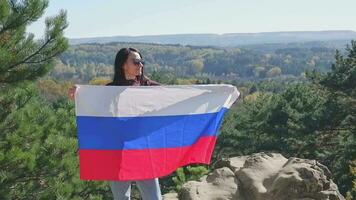 une brunette fille avec une russe drapeau contre le toile de fond de une magnifique paysage de le Caucase montagnes. russe indépendance journée video