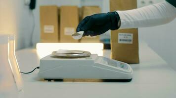 A laboratory technician pours mustard powder onto an electronic scale for weighing. Laboratory studies. Close up video