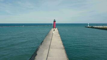 il grande rosso faro in piedi su il lago su il molo nel nuvoloso tempo atmosferico. il faro in piedi nel il porta di il lago. video