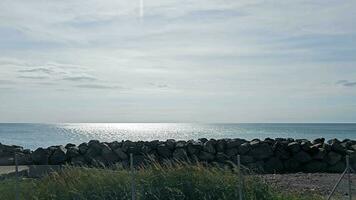 Tranquil Seaside View with Rock Barrier. A peaceful seascape with glistening waters shielded by a rugged rock barrier. video