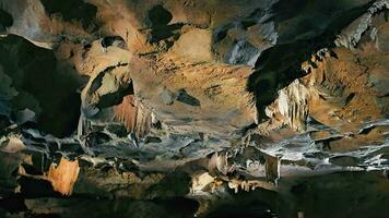 upplyst grotta interiör med stalaktiter och stalagmiter. vibrerande grotta formationer belyst upp avslöjande invecklad detaljer och texturer. video