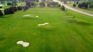 Aerial view of Golf course with trees, bushes and players. Flying over golf course while tilting down, showing the holes. video