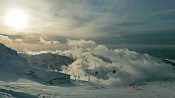 Eslovaquia, Jasna 12.01.2024 nublado cielo terminado montaña góndolas, góndolas Moviente mediante niebla terminado un cubierto de nieve pendiente. video