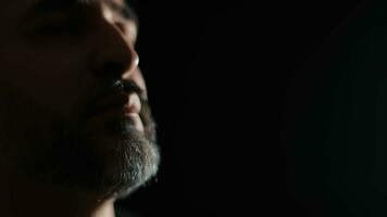 Face of a middle-aged man with a gray beard close-up on a dark background. video