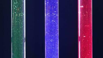 Tri-color LED Light Tubes. Three vertical LED tubes in green, blue, and red colors isolated on dark. video