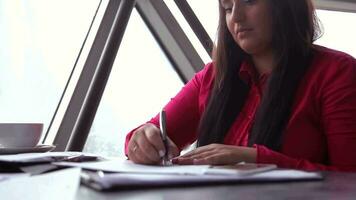 Close-up. Young beautiful business woman with dark long hair works with office documents and answers a call on a mobile phone video