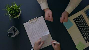 business man rejoices at signing a contract and shakes hands with a partner sitting at the table. overhead shot. slow motion video