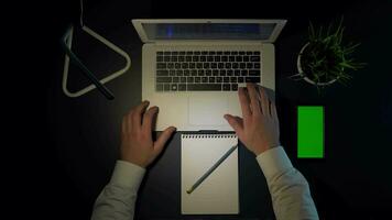 man working sitting at the table using laptop and phone overhead shot.4k video