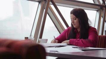 Business woman with dark long hair is working with office documents in the office. video