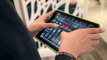 The DJ adjusts the sound by holding the control panel and adjusting the mixer. video