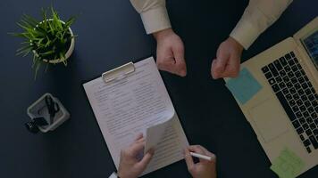 business man rejoices at signing a contract and shakes hands with a partner sitting at the table. overhead shot. slow motion. HD video