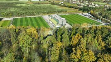 Aerial View of a Soccer Field and Clubhouse, Aerial shot of soccer fields beside modern clubhouse and parking, with autumn trees. video