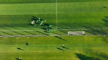 calcio formazione sessione a partire dal sopra, superiore Visualizza di calcio Giocatori su verde campo durante formazione sessione, circondato di alberi. video