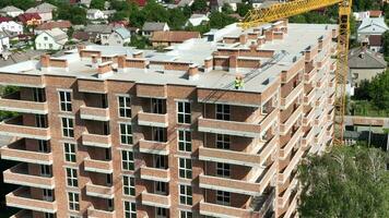 un' volo al di sopra di un' grattacielo rosso mattone edificio con inserto finestre senza un' facciata. il Casa è sotto costruzione a partire dal mattoni. video