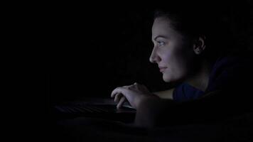 atraente feliz feminino menina digitando em computador portátil teclado deitado em cama às noite. isolado luz 4k video