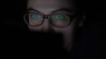 attrayant content Jeune fille dans des lunettes fait du en ligne achat par mobile ordinateur mensonge sur le lit à Accueil à nuit. isolé lumière 4k video