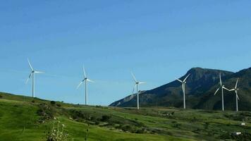 viento turbinas en el montañas Moviente con azul cielo un soleado día video