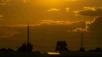 eléctrico polos y alambres en el puesta de sol cielo y Moviente nubes en el antecedentes en el campo. video