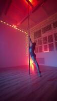 Elegant Woman Performs a Pole Dance Under Neon Lighting. Vertical Video