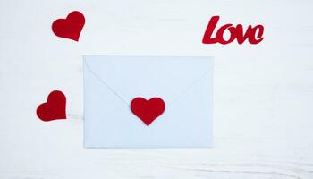 Romantic message for Valentine's day. Flatlay composition with envelope and red hearts for Valentine's day on white background. Top view. photo