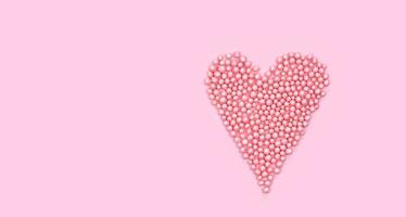 Heart shape made of small pink balls on pink background. Creative composition for Valentine's Day. Top view. Copy space. photo