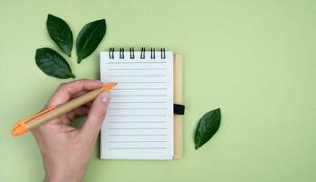 Young woman using a notepad and pen made of eco friendly materials. Top view. Banner. Place for text. photo