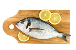 Raw fish Dorado with lemon on a cutting board isolated on a white background. Top view. photo