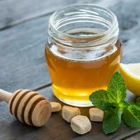 Honey in jar with honey dipper on vintage wooden background photo