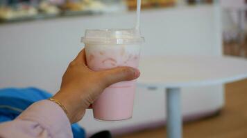 Strawberry drink or Pink drink cup held by hand from the side photo